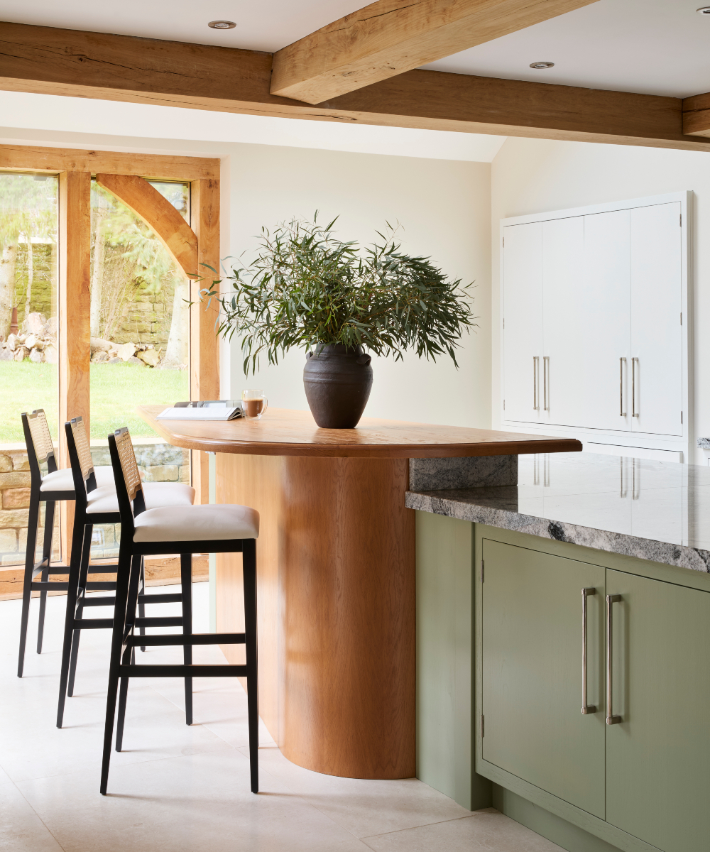 Bright kitchen in a modern heritage home showcasing a large island and comfortable bar chairs, creating a welcoming space for meals and conversation.