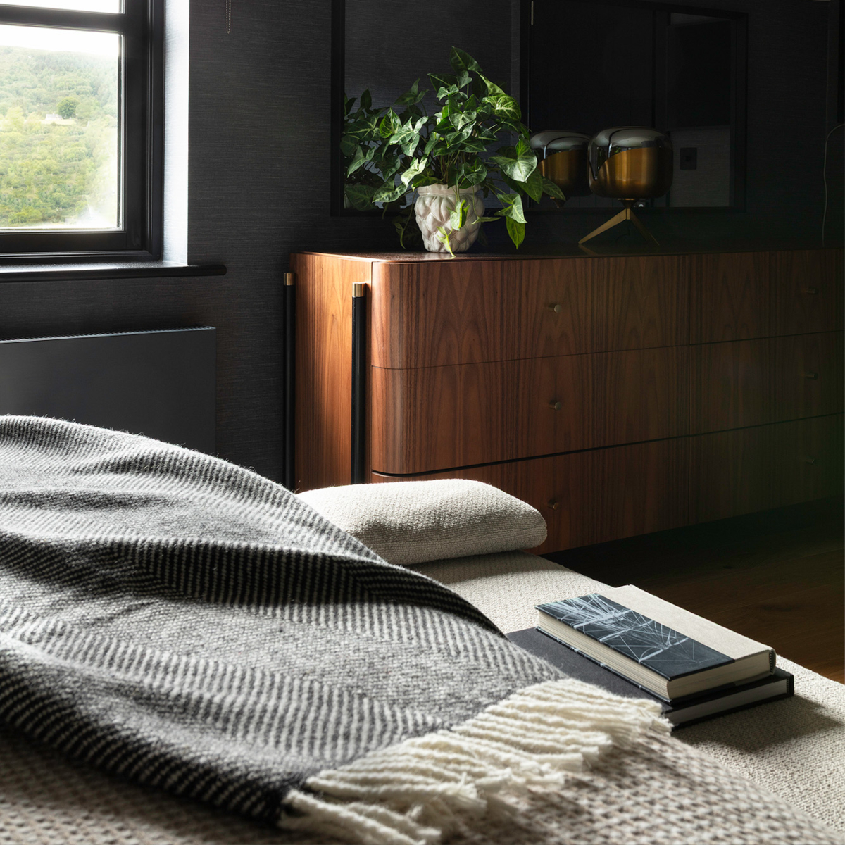 A neatly made bed with a soft blanket and a book placed on the nightstand nearby.