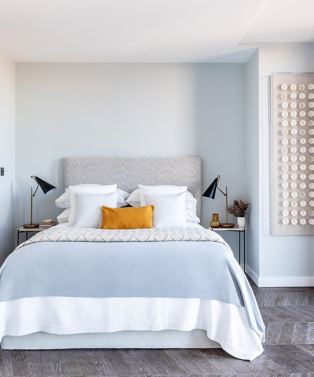 A serene bedroom with a white bed and soothing blue walls.