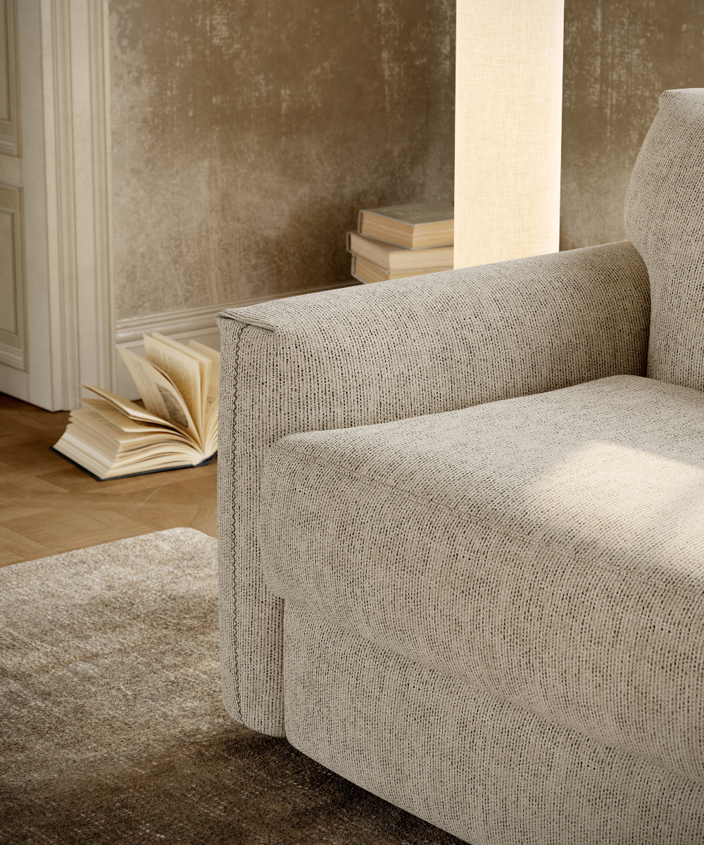 A comfortable sofa bed sits in a living room, with a book resting on the floor beside it.