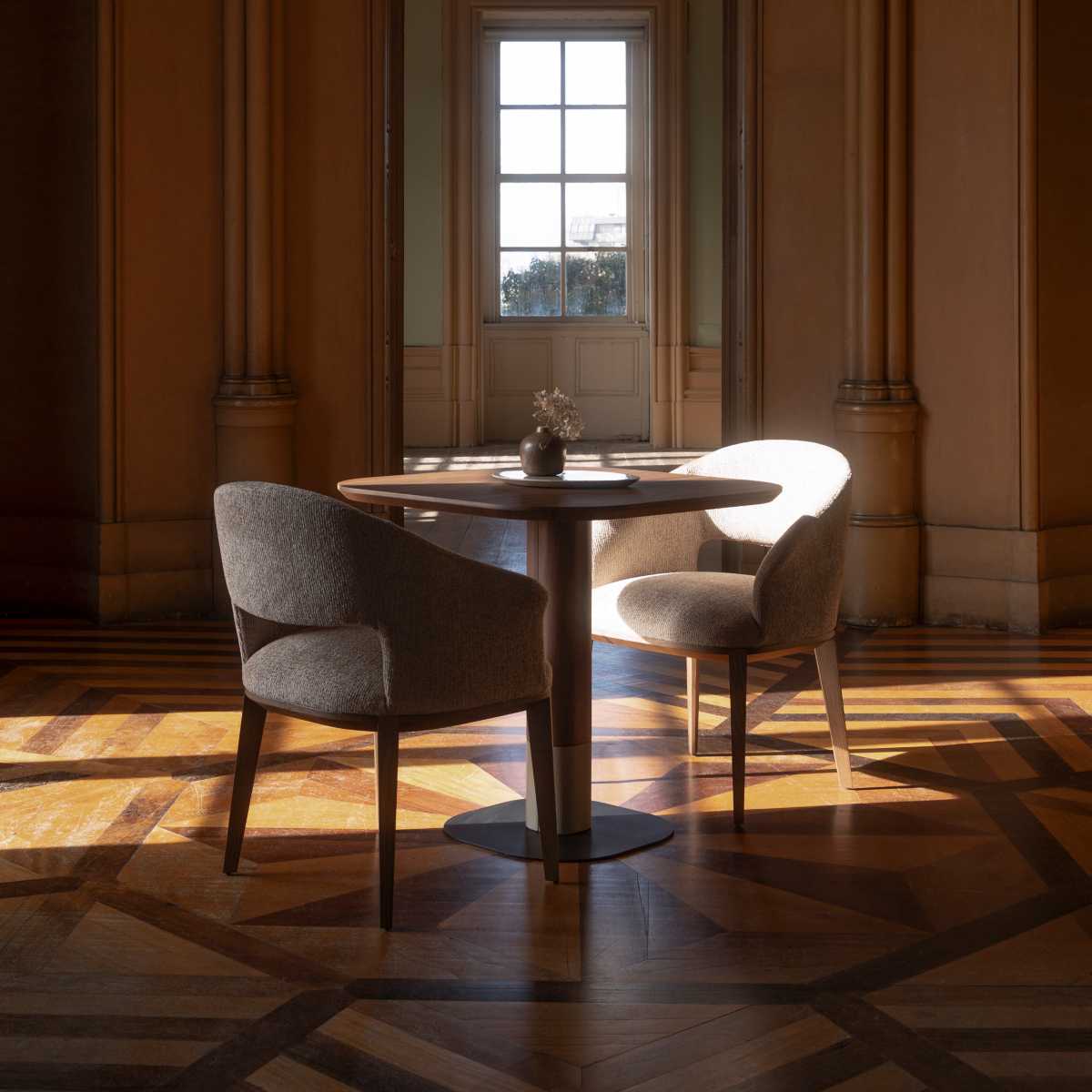 A cosy dining room with a table and two dining chairs beside a large window, creating a welcoming atmosphere. 2025 dining room trends.