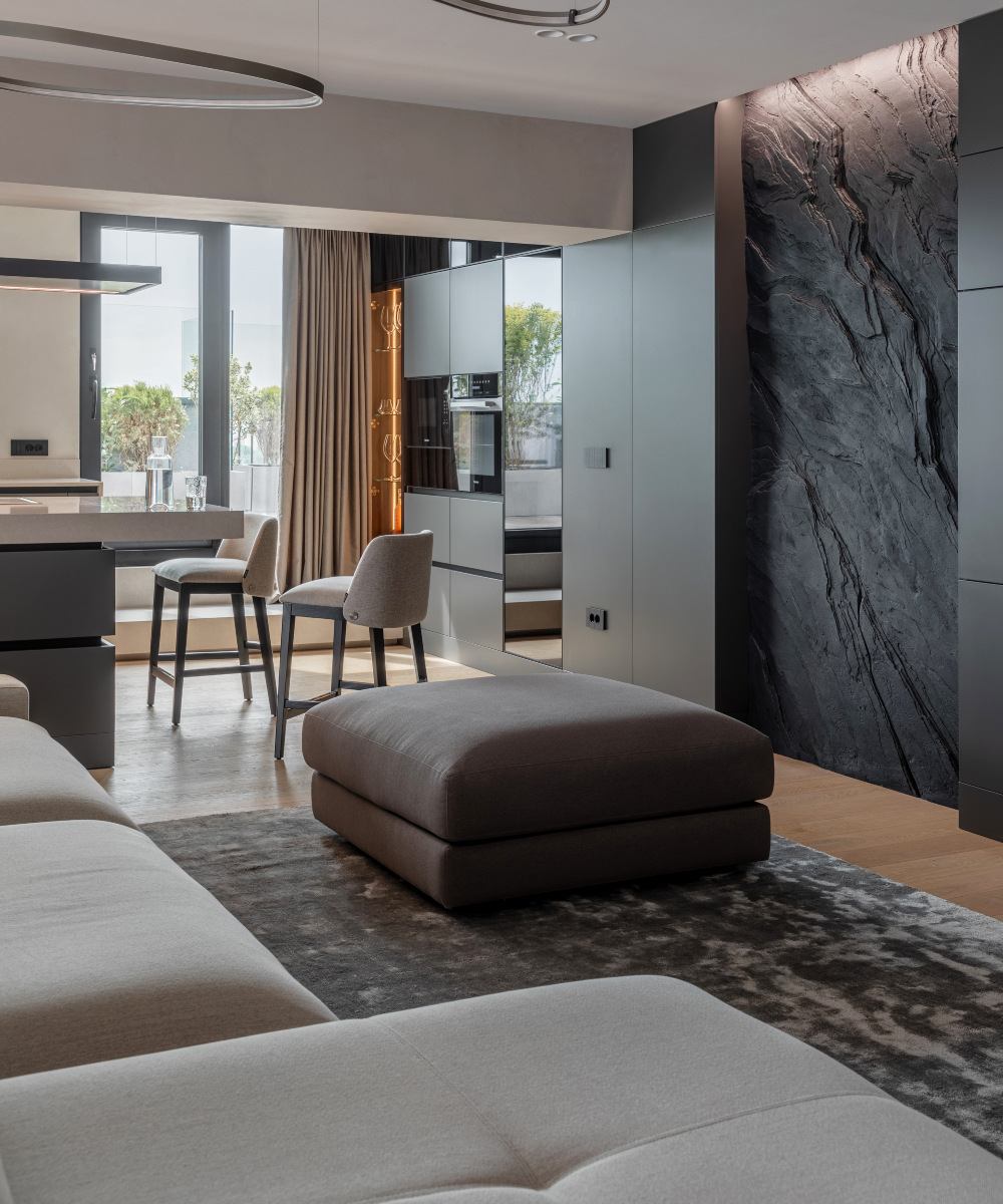 Spacious modern living room and kitchen showcasing a striking stone wall, complemented by chic decor and ample natural light.