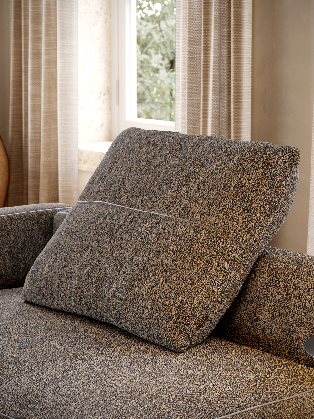 A comfortable modular sofa adorned with a pillow, located in front of a large window.