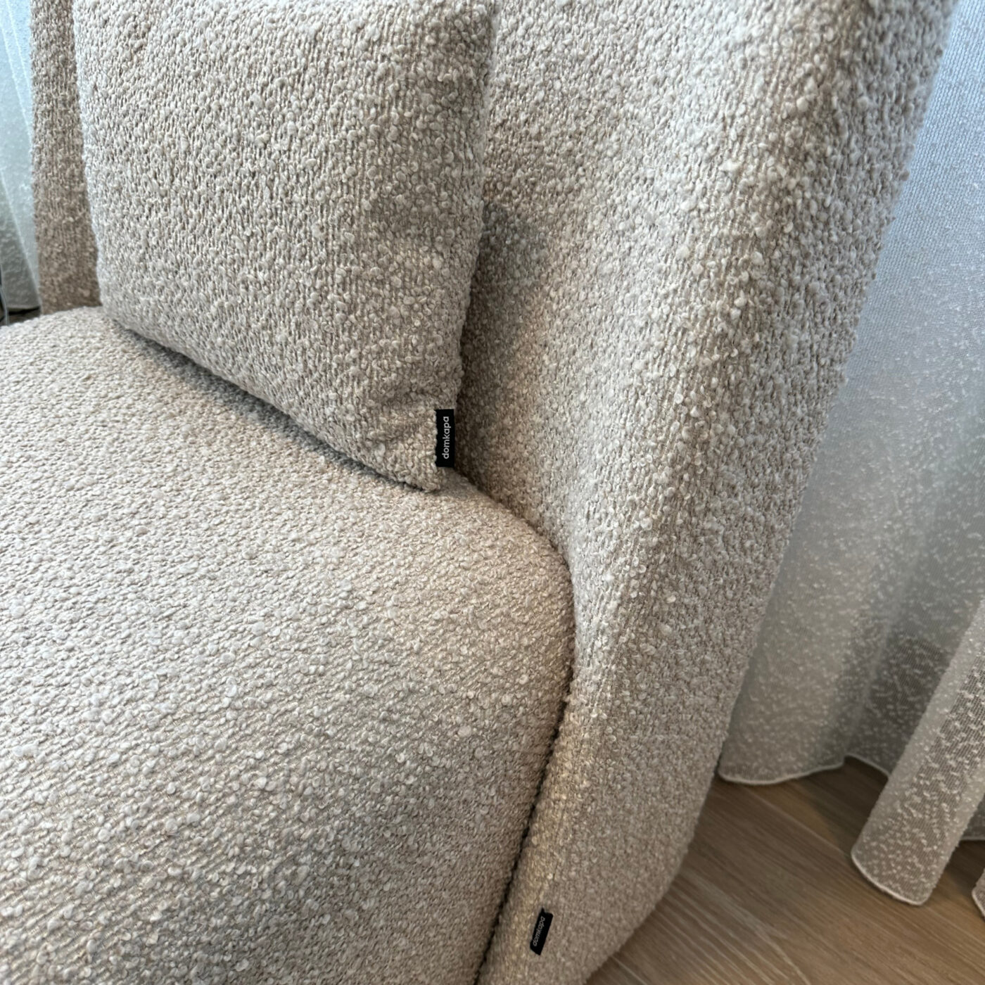 Two elegant armchairs in boucle placed in front of a window, draped with curtains, enhancing the room's inviting ambiance. Project by Etch & Notch Design's.