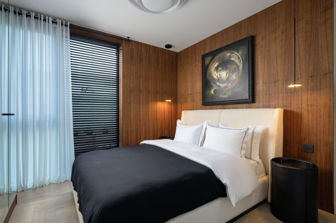 A stylish bedroom designed by Loredana Todor, showcasing a bed, a decorative painting, and a window that brightens the space with sunlight.