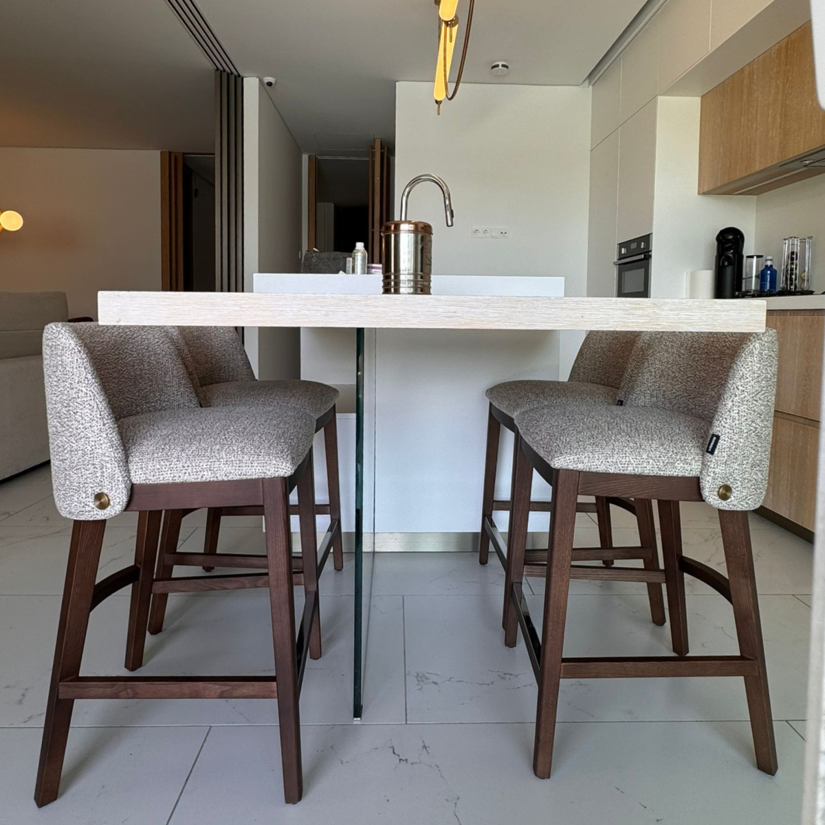 A kitchen scene featuring a table with four counter chairs and a sink, ideal for meals and food preparation.
