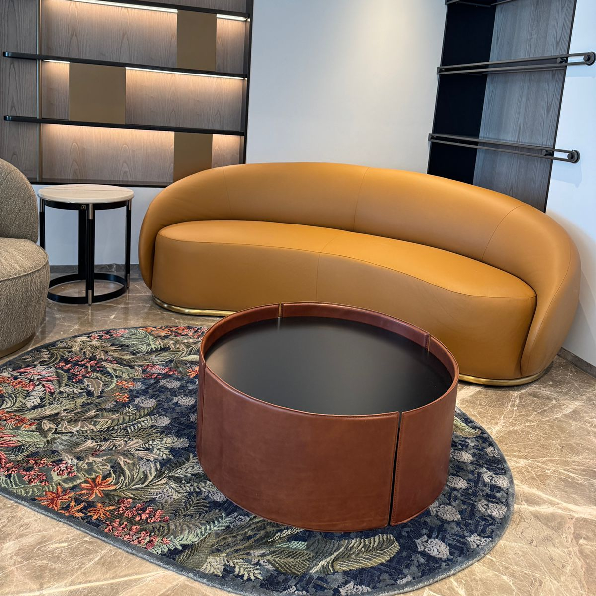 A modern living room featuring a round sofa and a leather coffee table, creating a cosy and inviting atmosphere.