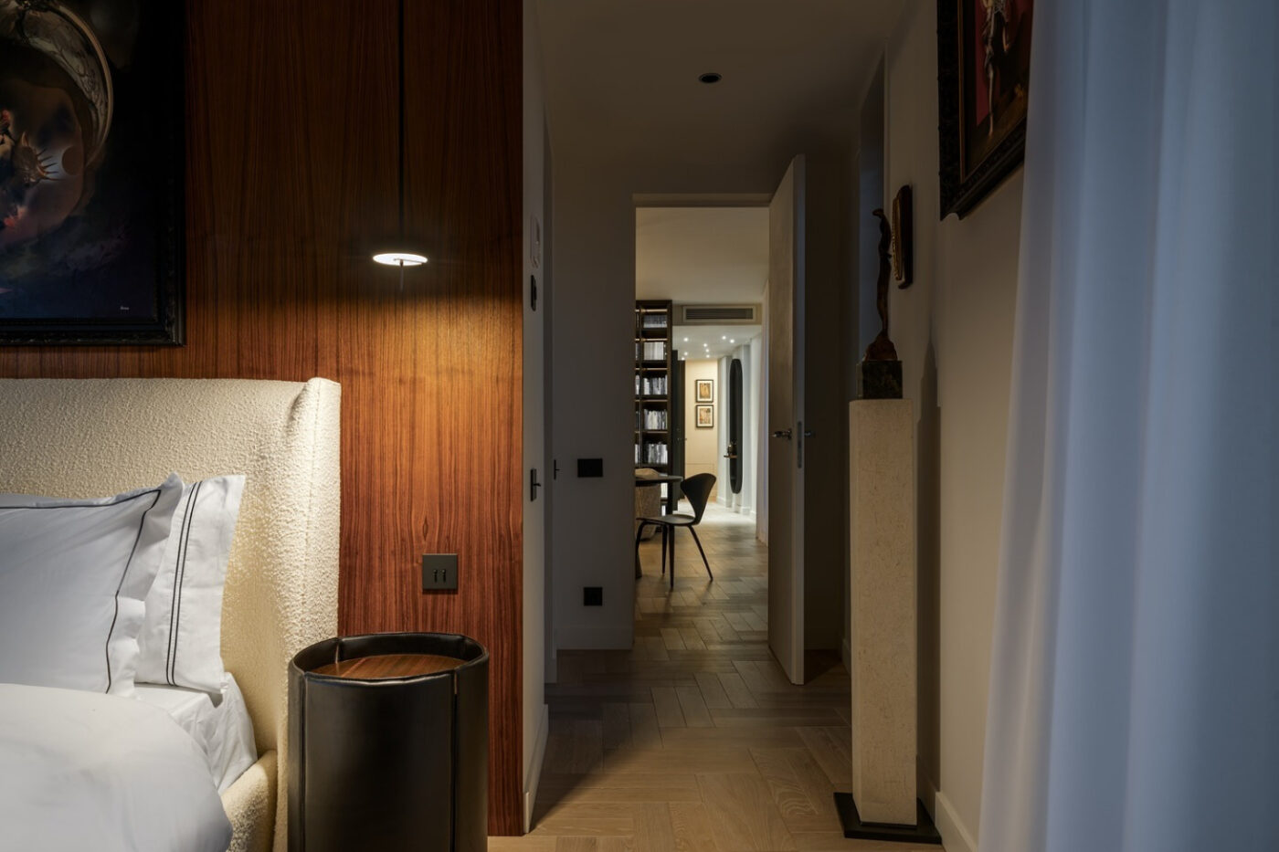 A cosy bedroom desigend by Loredana Todor featuring a neatly made bed and a wall-mounted television for entertainment.