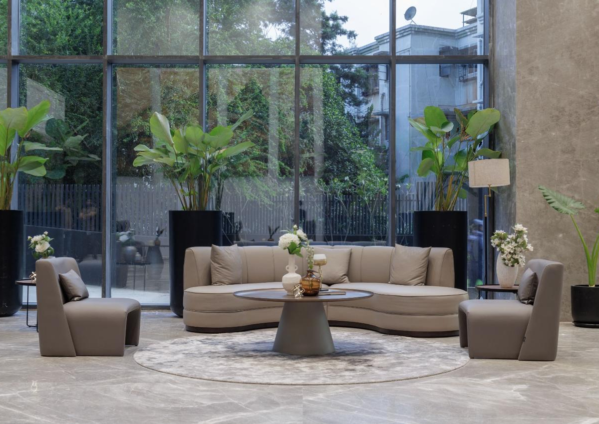 A modern lobby featuring large windows and tall plants, creating a bright and inviting atmosphere. By one of the best Asian interior designers.