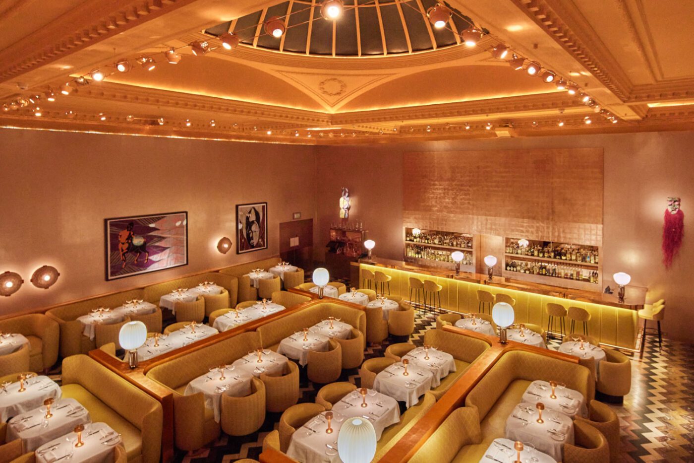 sketch-gallery-1920x1080 (1) Elegant restaurant interior with yellow booths, white tablecloths, and soft globe lights. Art decorates the walls, while a stocked bar adds warmth and luxury. One of the best designed restaurants in London