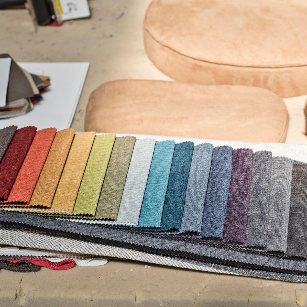 upholstery grades by domkapa (1) Fabric swatches displayed on a table beside a chair, showcasing various hues for design selection. Upholstery grades